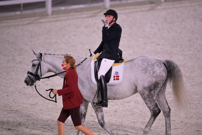 Tobias Jorgensen, a Para equestrian athlete from Denmark, blows a kiss while riding a white horse at the Tokyo 2020 Paralympics.