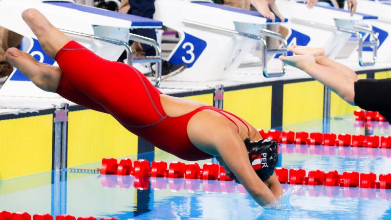 a female Para swimmer with no legs dives into the pool