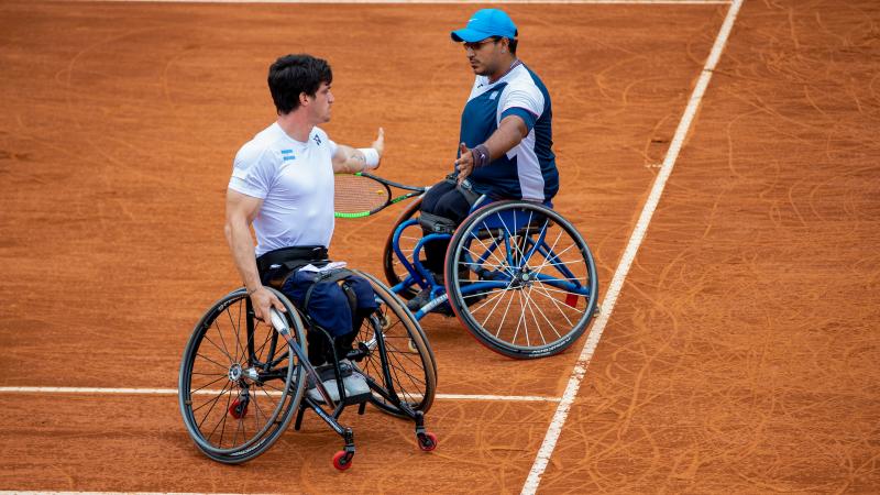 two male wheelchair tennis players high five on court