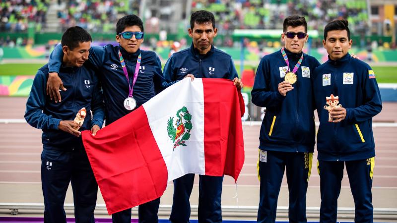 a group of vision impaired runners on the podium holding a Peru flag