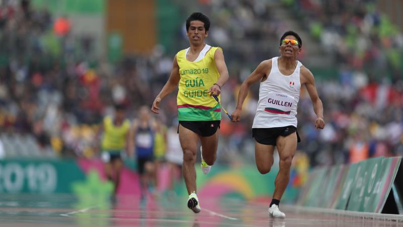 a male vision impaired runner and his guide sprinting to the finish line