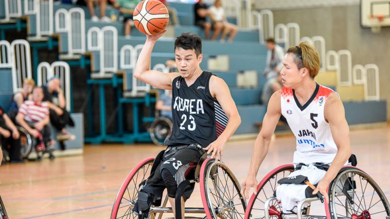 Two male wheelchair basketball players contending 