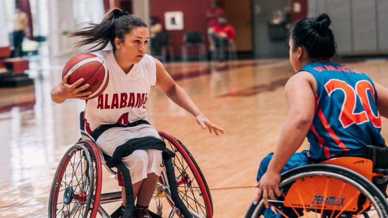 Woman playing wheelchair basketball tries to get around her defender