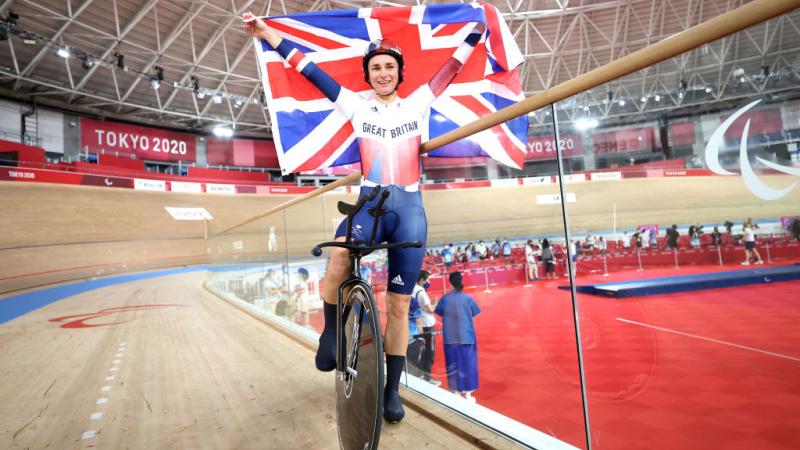 A female Para cyclist celebrates by holding the British flag