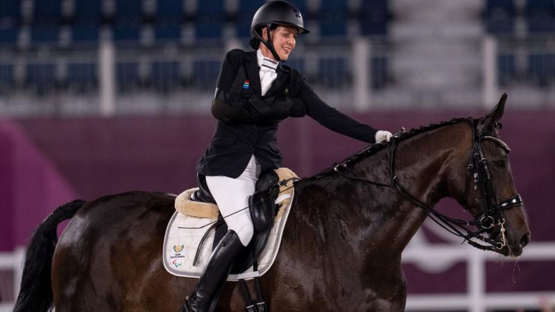 A female Para equestrian athlete rides a horse
