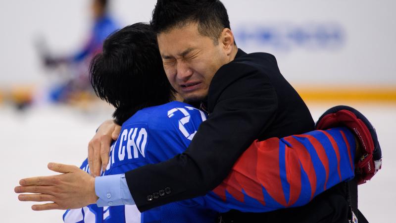 two men embrace and cry on an ice rink