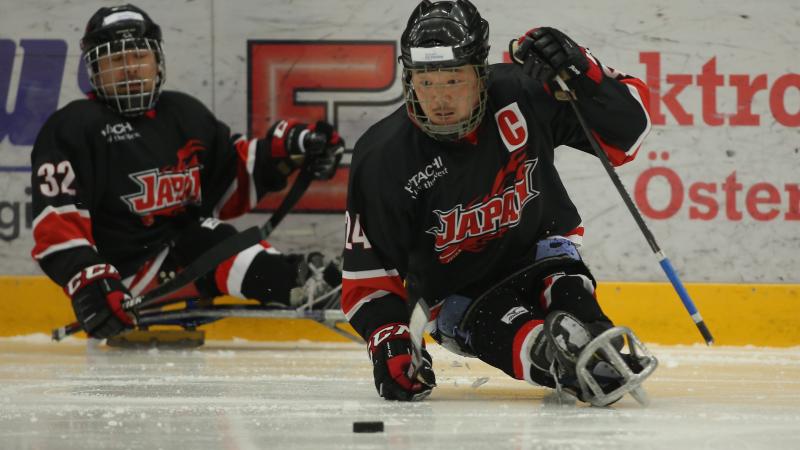 Japanese male Para ice hockey player skates with the puck