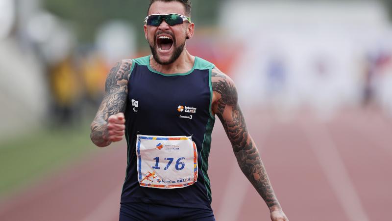 male Para athlete Vincent Rodrigues yells out as he crosses the finish line to win the race