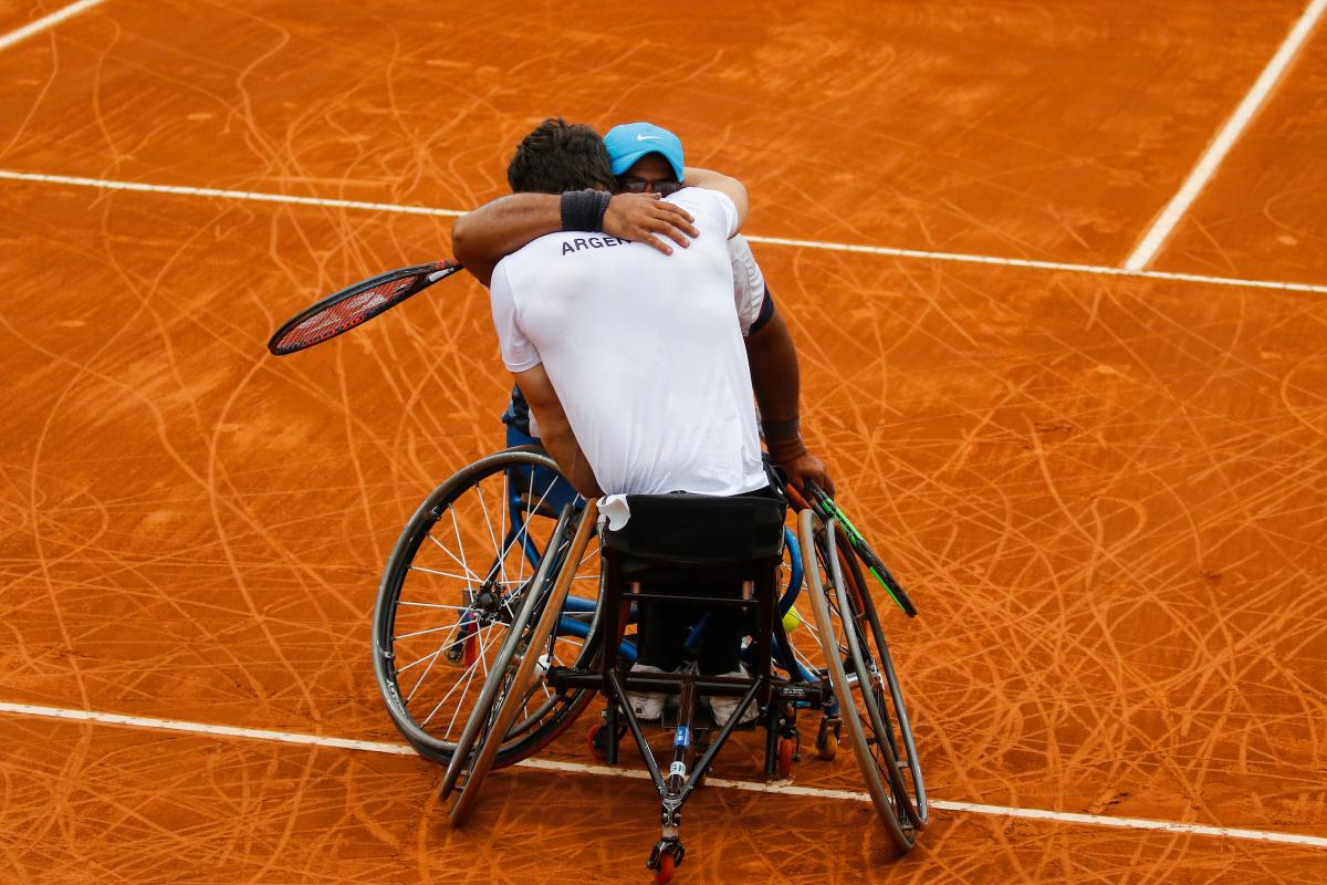 two male wheelchair tennis players hug on the court