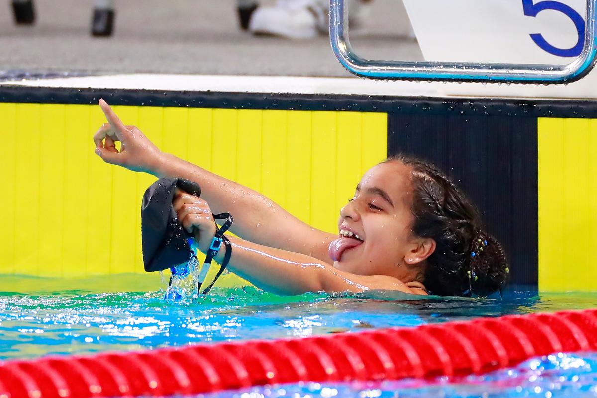 a female Para swimmer in the pool sticks her tongue out