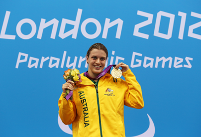 A picture of woman on a podium showing her gold medal