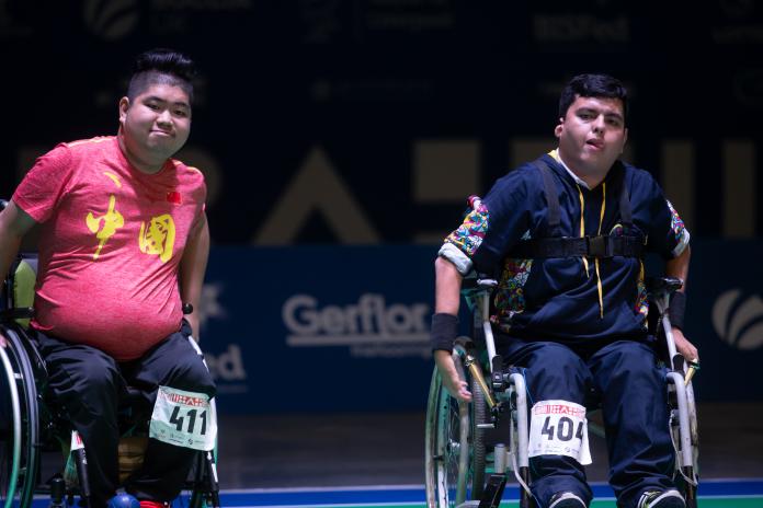 Two male boccia athletes watch the court