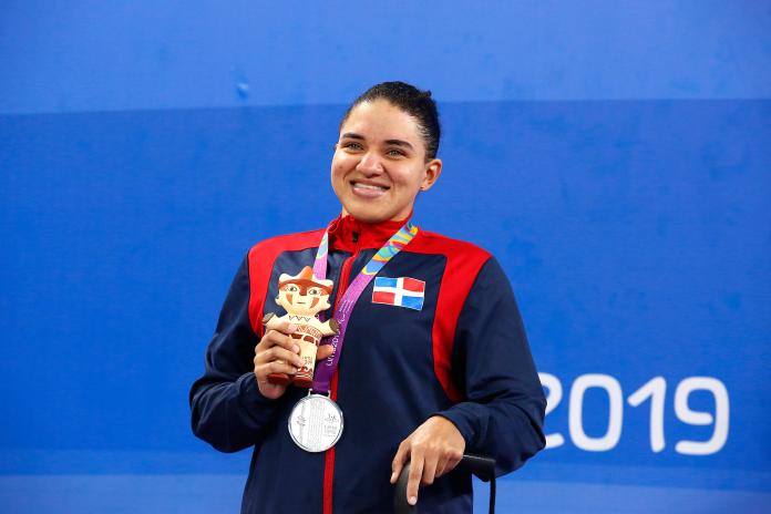 female Para swimmer holds up her silver medal on the podium