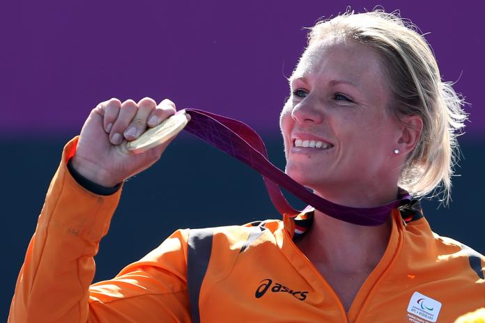 Dutch wheelchair tennis player smiles holding her gold medal at the London 2012 Paralympics