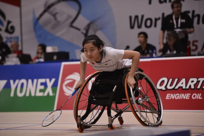 Badminton player pushing her wheelchair forward on the court
