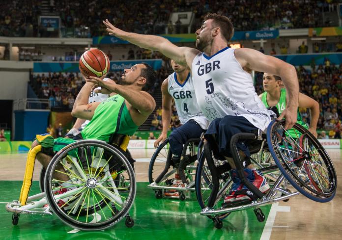 Man tilts his wheelchair to block his opponent trying to shoot the basketball