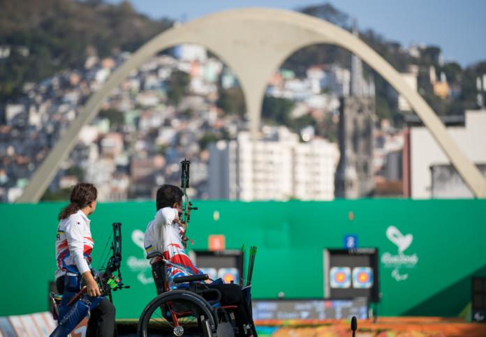 South Korean archer aims at the target with his teammate looking next to him