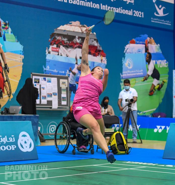 Female badminton athlete with arm impairment leaps to return shuttle