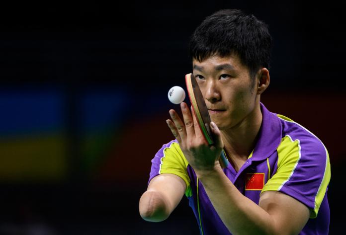 Chinese male table tennis with missing right arm serves ball