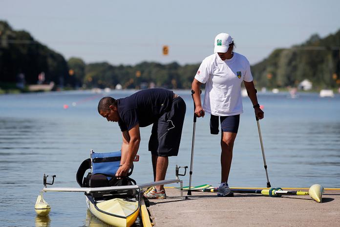 Woman with leg amputation and crutches waits for her assistant to set up her rowing boat