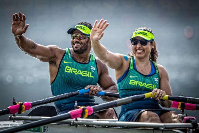 Male and female Brazilian rowers smile and wave at the crowd