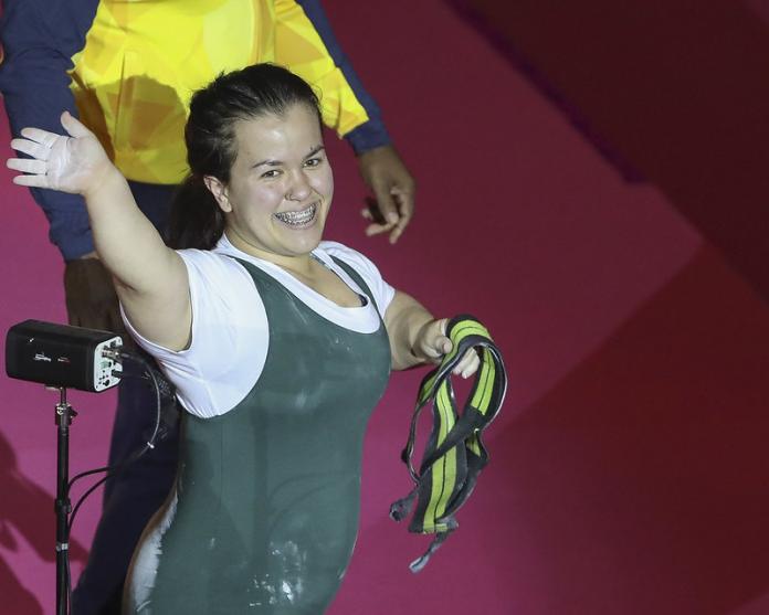 Brazilian female powerlifting smiles waving at the crowd after a lift