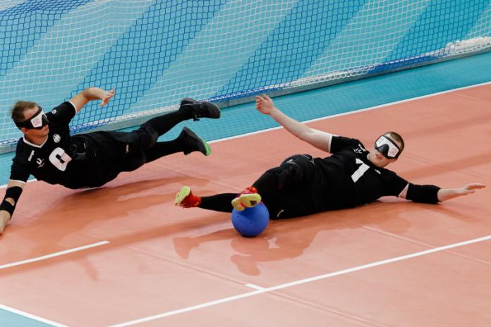 Two German goalballers dive to stop the ball from entering their goal
