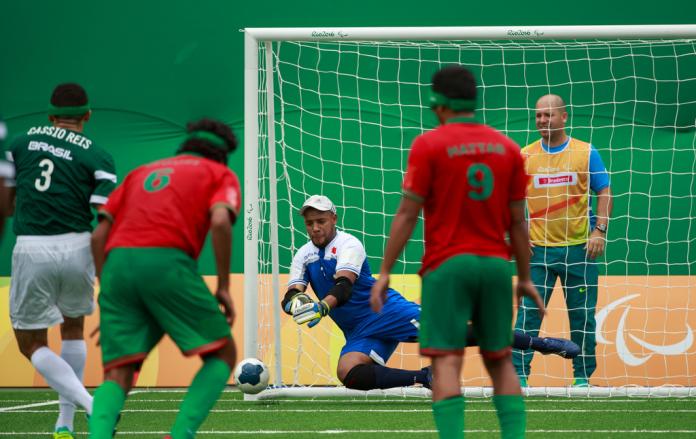 Goalkeeper attempts to block a shot in football 5-a-side