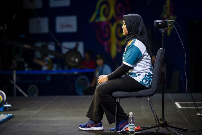 Female powerlifting judge sits and observes