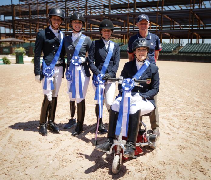 Female equestrian riders pose for a photo with their male coach in the back