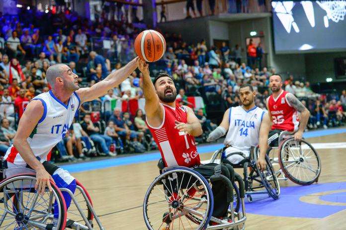 Turkish wheelchair basketball player Ismail Ar shoots while an Italian defender tries to block him
