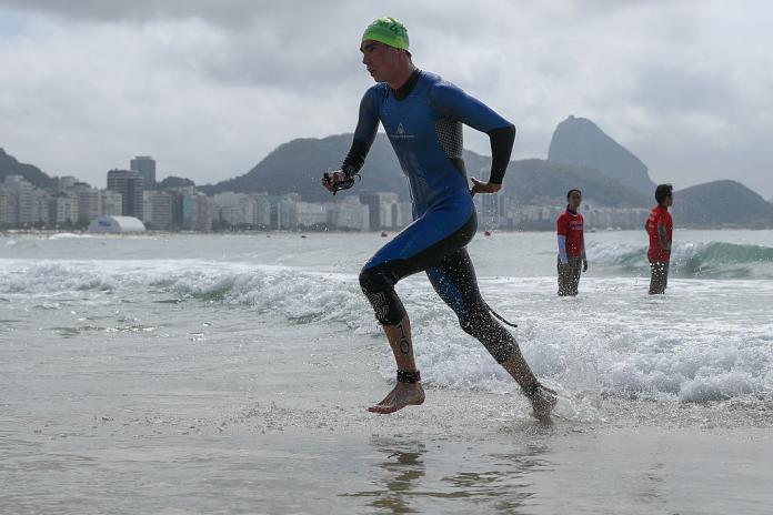 Triathlete emerges out of water in wetsuit