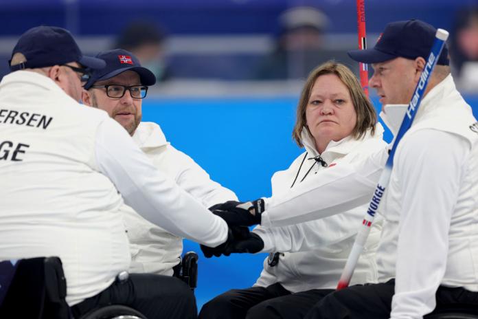 A group of Norwegian wheelchair curlers gather to discuss tactics