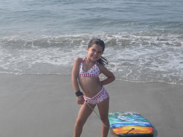 Anastasia Pagonis smiles and poses on the beach as a child.