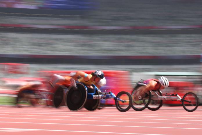 A blur of wheelchair races, including Madison de Rozario in second position, race in the women's 5000m T54 final at Tokyo 2020.