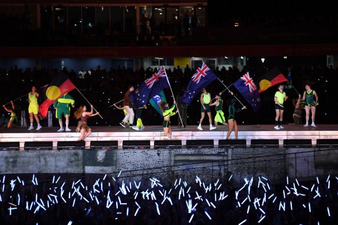 Dancers with Australian flags perform on stage as glow sticks light up in the crowds below.