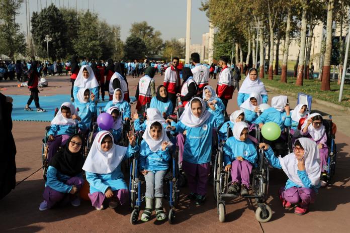 Children in wheelchairs pose for a photo in T-shirts that read "Paralympic Day".