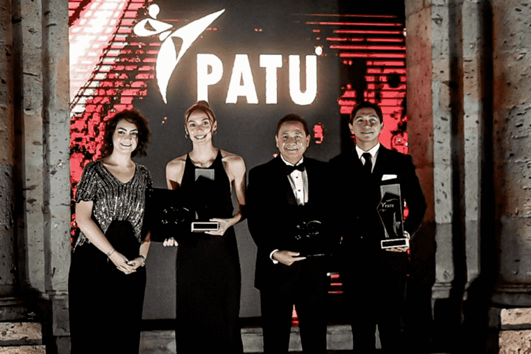 Two women and two men in formal attire pose with trophies at an awards gala.