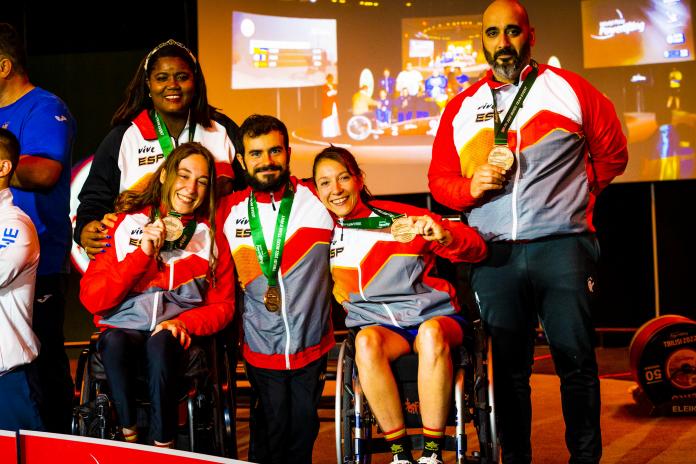 Five Spanish athletes and coaches smile and show their bronze medals as they pose for a photo after the medal ceremony. 