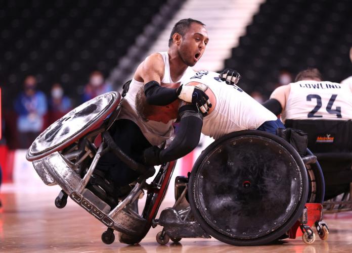 Two male wheelchair rugby players hugging in celebration