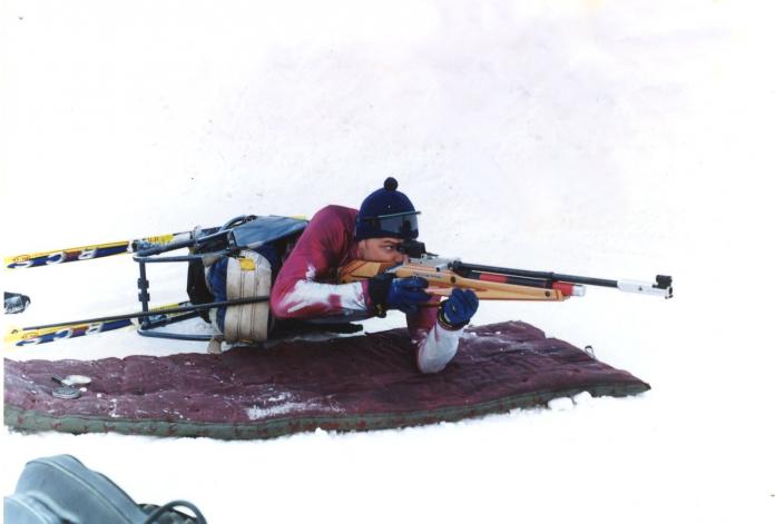 A male athlete aims a rifle during a Para biathlon event.