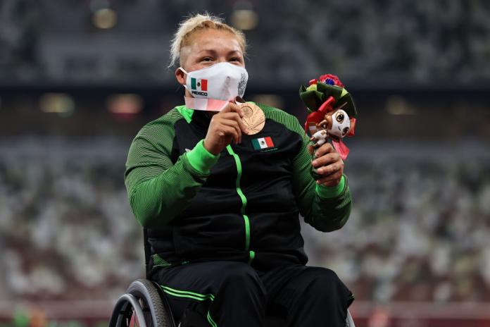 A female wheelchair athlete holds up a Paralympic bronze medal