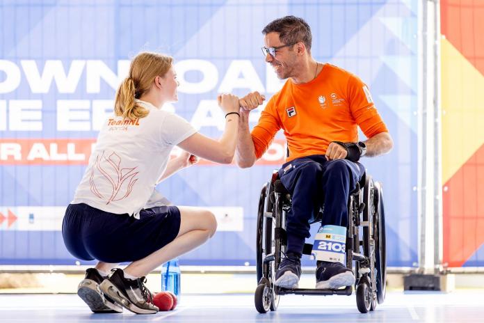 A male athlete and a female official wearing a Tshirt that says "Team NL boccia" celebrate
