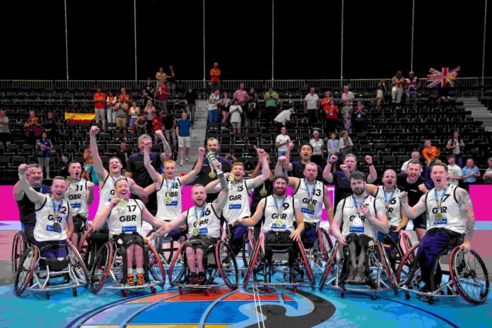 A group of about 20 wheelchair basketball players and official pose for a group photo