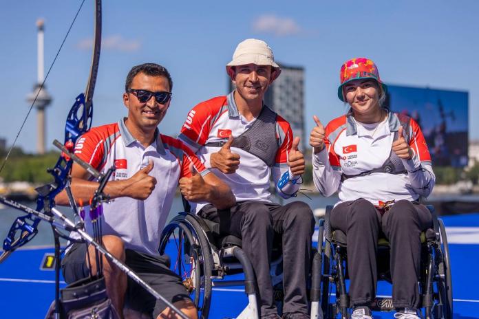 Two male and one female Para archer giving a thumbs up on the podium 