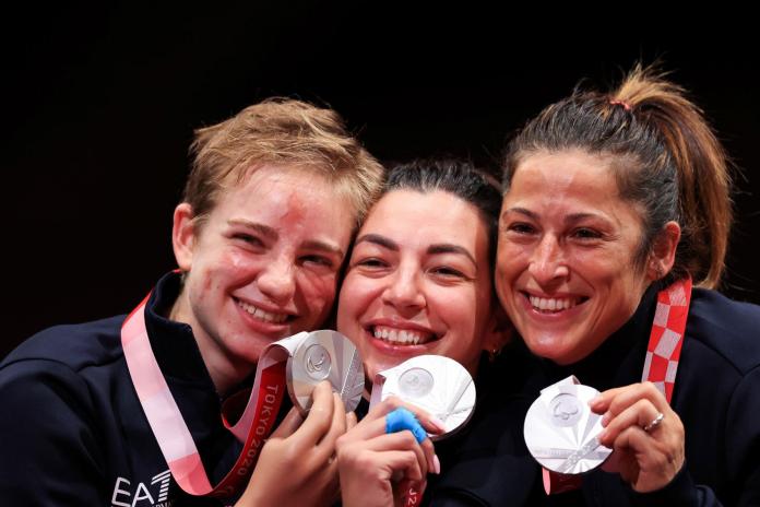 Three female athletes pose for a photo with their silver medals at Tokyo 2020