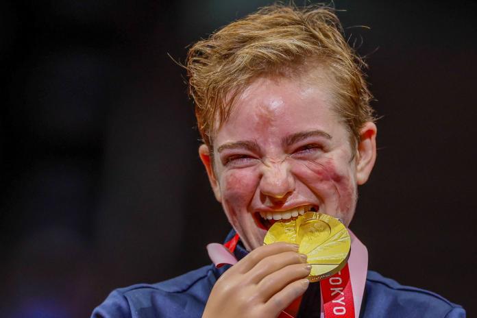 A female athlete bites a gold medal