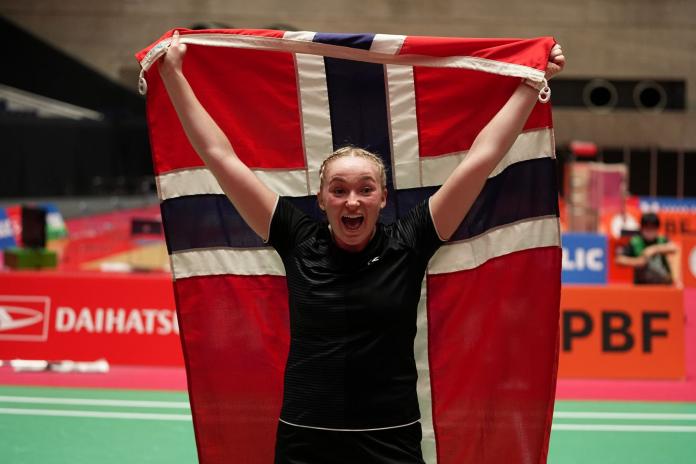 A female Para badminton player raises the flag of Norway
