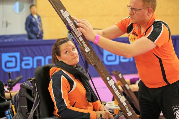 Sonia Heckel, a boccia athlete from France, looks at the blue ball set on a ramp by a male sport assistant.