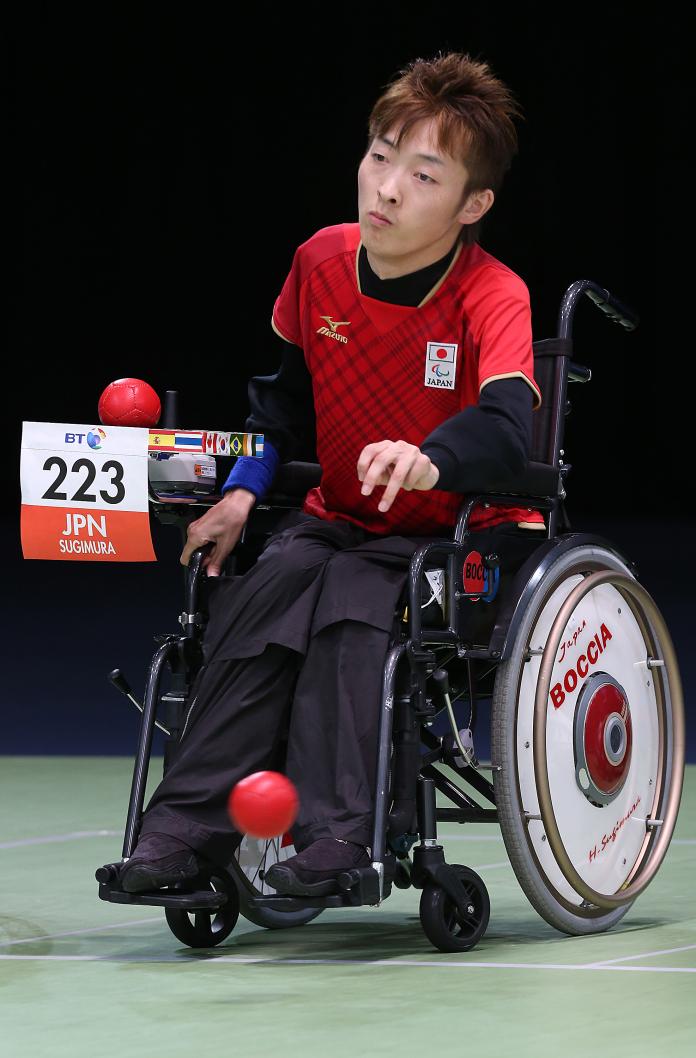 Man in wheelchair throwing a red boccia ball